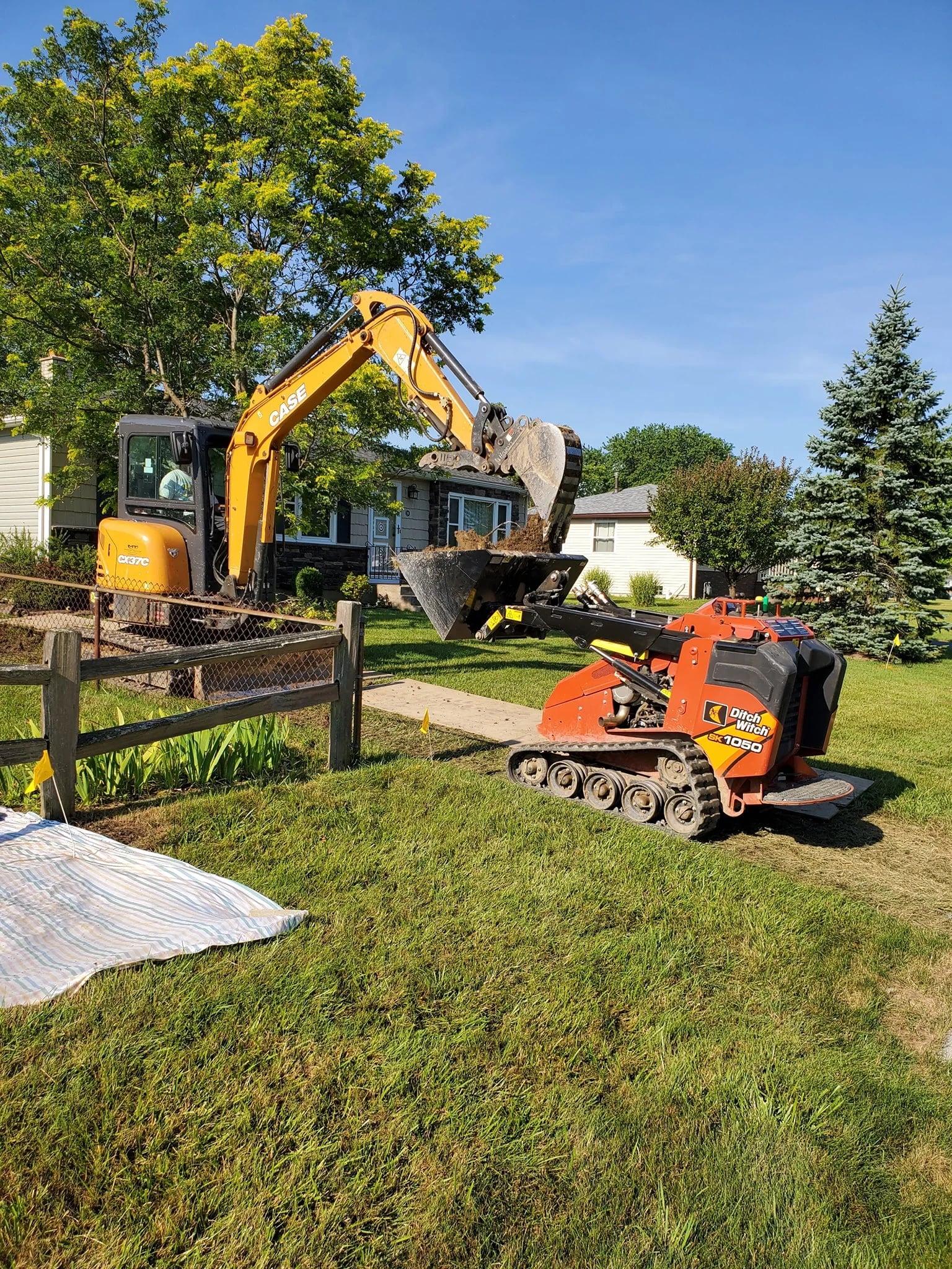 Case excavator loading Ditch Witch loader in Erie County residential yard