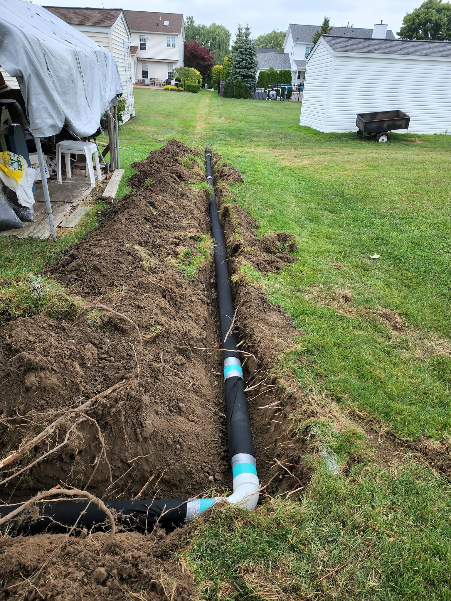 Black corrugated drain with PVC couplings and fabric in WNY backyard