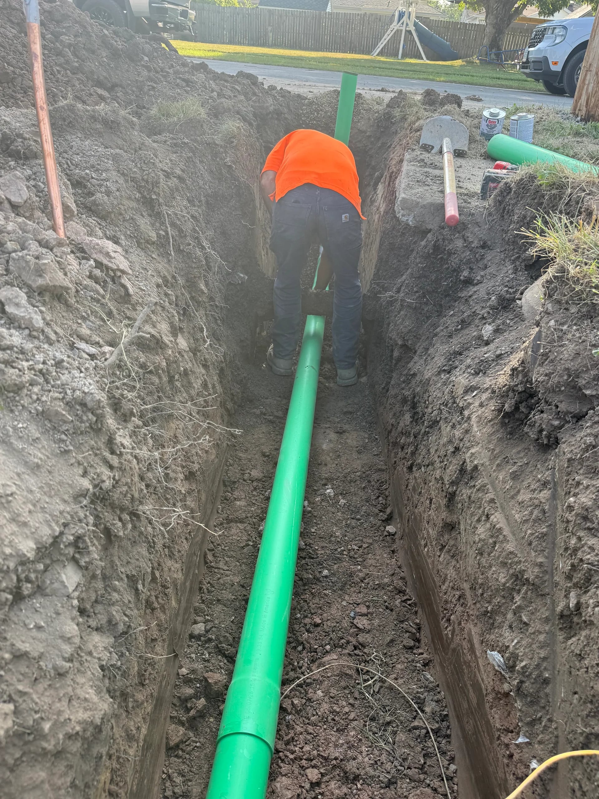 Technician connecting green sewer pipes in deep trench at Buffalo area home