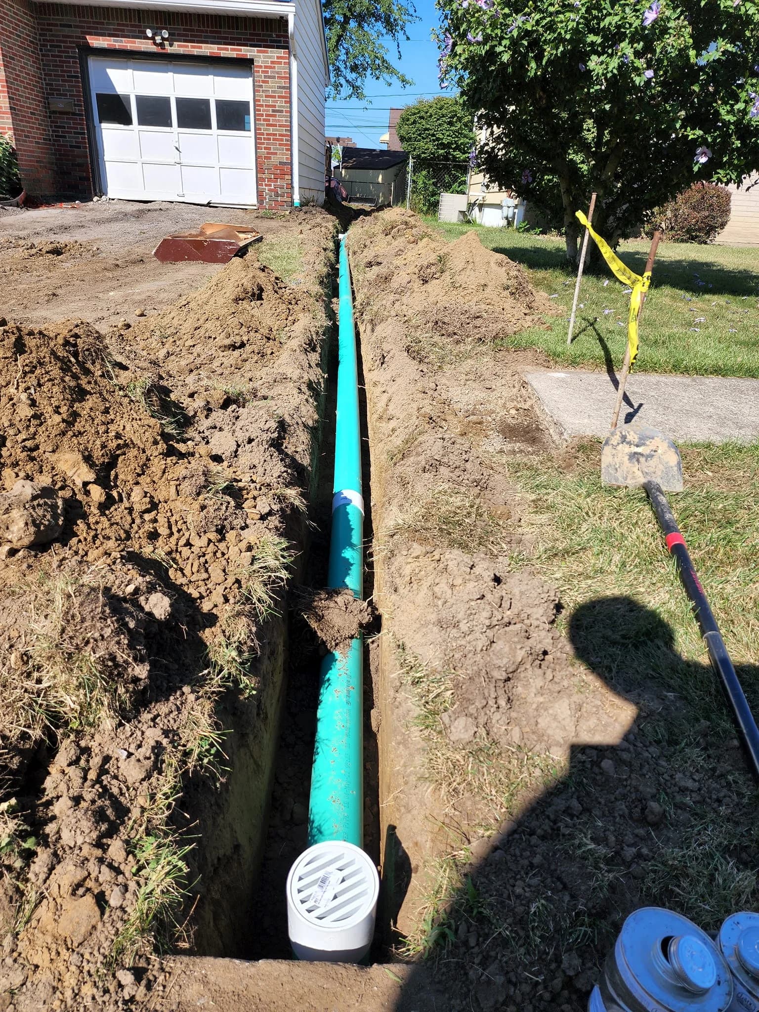 Green PVC sewer drain from garage to sidewalk in Tonawanda front yard