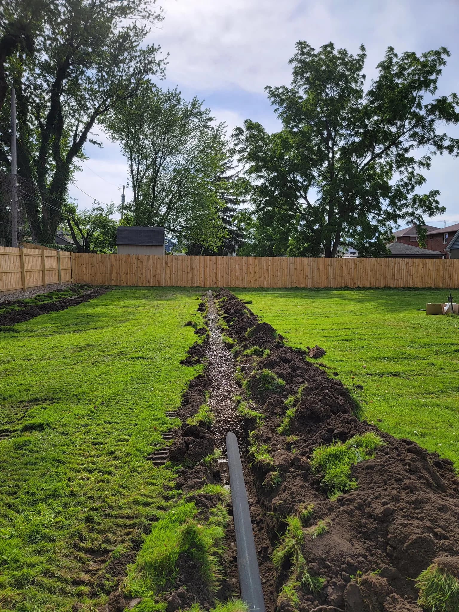 Gravel-backfilled drainage trench across lawn in Erie County neighborhood