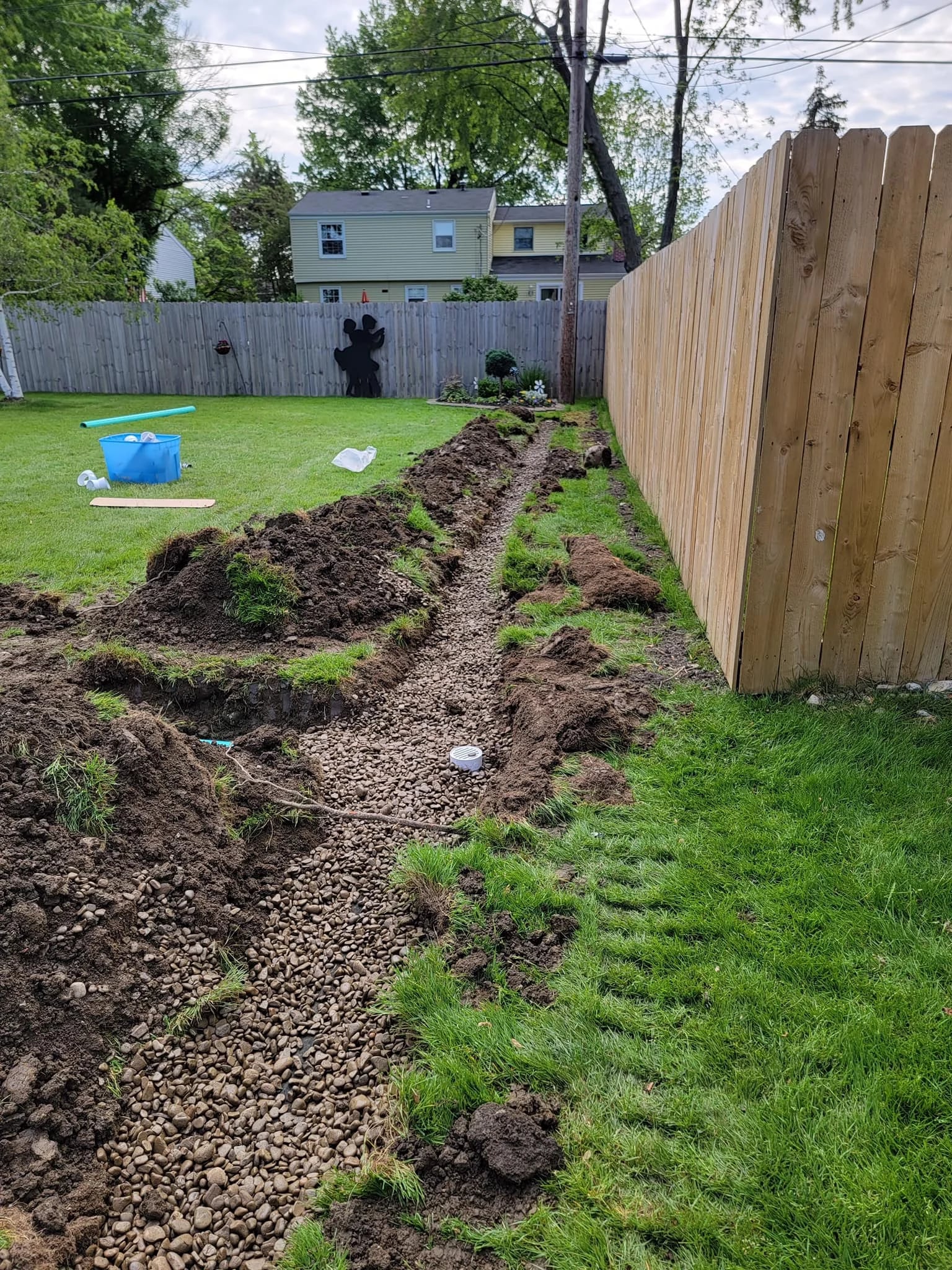 French drain installation along wood fence in Buffalo area backyard