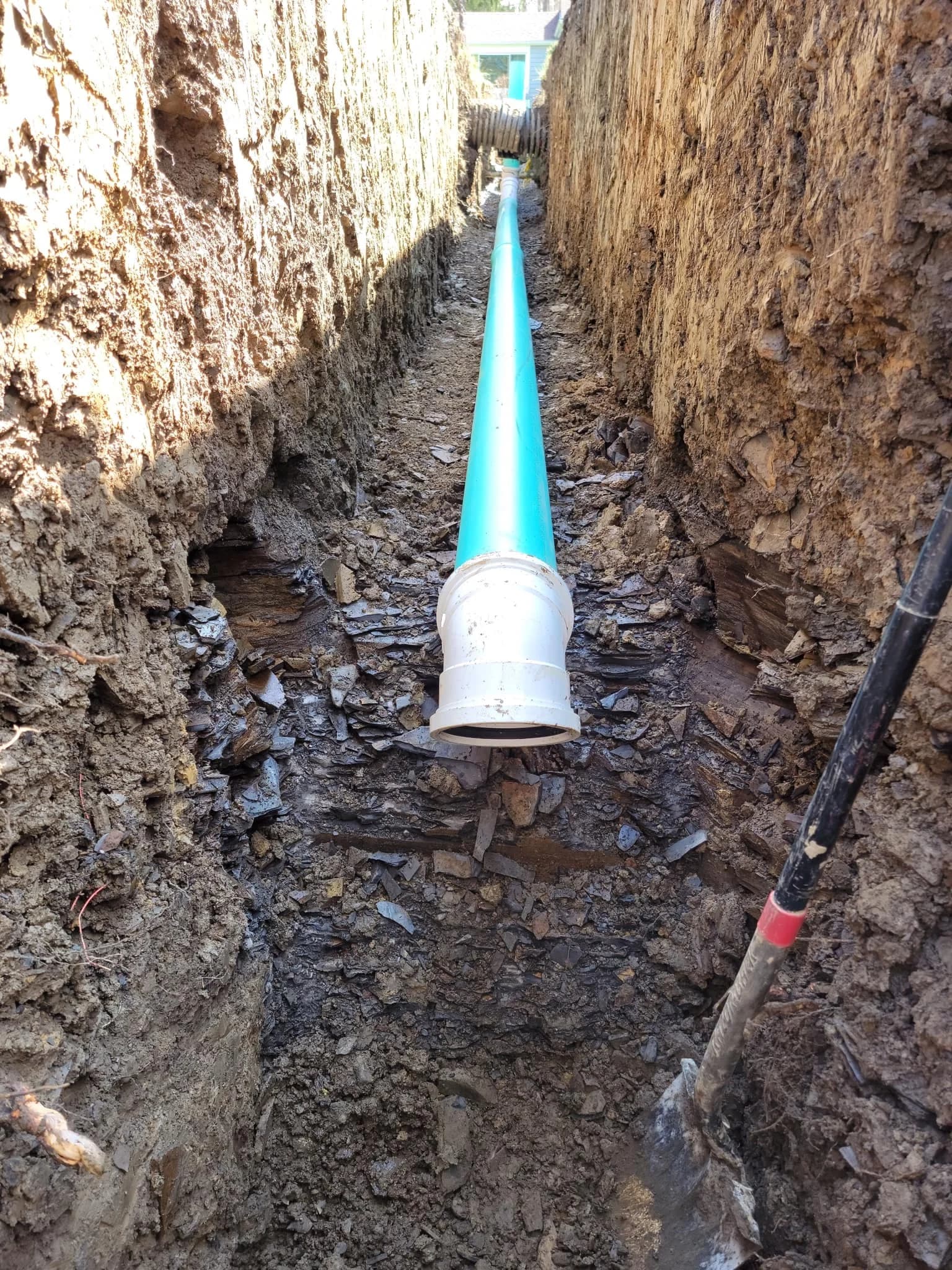 New PVC sewer with cleanout in deep Lackawanna yard trench with shovel