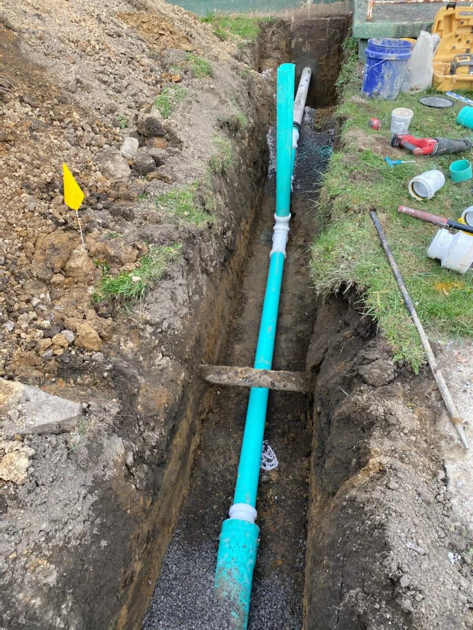 Green PVC sewer with cleanouts and flag in South Buffalo yard trench